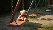 © Prapat - Morning sunshine on surface of little teddy bear sitting on swing set in playground at public park
