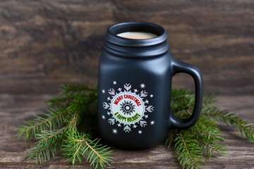 Wall Mural - Christmas, new year concept with mug of hot coffee with milk against rustic wooden background with spruce branches. Selective focus.