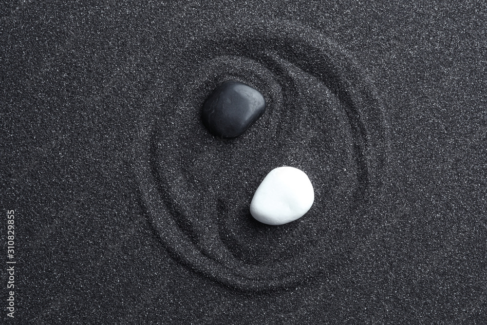 Yin Yang symbol made with stones on black sand, top view. Zen concept - obrazy, fototapety, plakaty 