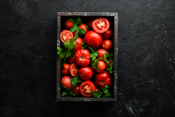 Fresh red tomatoes in box on black stone background. Vegetables. Top view. Free space for your text.