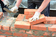 Bricklayer hands in masonry gloves and trowels bricklaying house wall. Building contractors bricklaying house wall,  masonry.