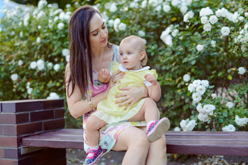 Happy mother and daughter in the park. Beauty nature scene with family outdoor lifestyle. Happy family resting together on the green grass, having fun outdoor. Happiness and harmony in family life