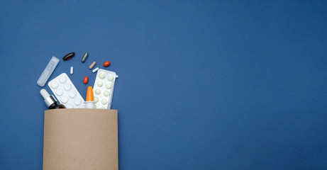 pharmacy and drugstore online concept. medicine pills in a paper bag on blue background, space for t