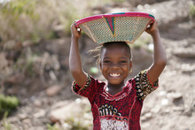 Body Shot Of Cute African Young Girl Carrying Food Basket And Blurred Background