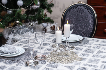 Set Christmas table for two person in cosy living room in silver colors