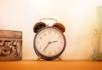 Retro alarm clock on wooden ton the shelf, vintage style.