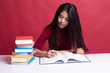 © halfbottle - Young Asian woman read a book with books on table.