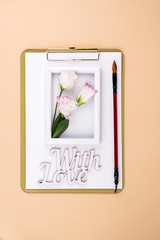 Canvas Print - Clipboard with eustoma flower and white frame on beige paper background, flat lay. Post card mockup