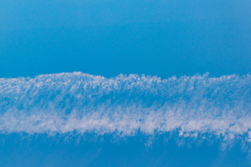 Wall Mural - A band of white clouds on a blue sky background