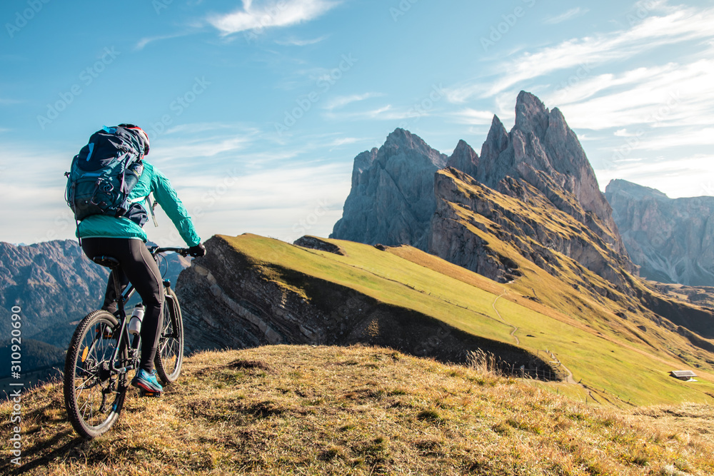 Young man with mountain bike cycling on Seceda mountain peak at sunrise. Puez Odle, Trentino, Dolomites, Italy. - obrazy, fototapety, plakaty 