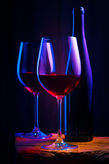 Two glasses of red wine with bottle on wooden table and dark background. Intimate atmosphere. Romance concept