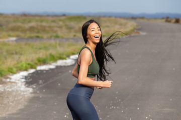 Pretty African American woman smiling as she works out on quiet country road alone