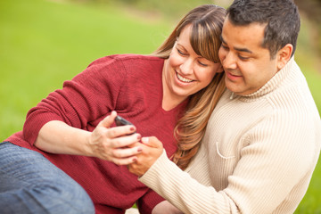 Wall Mural - Attractive Mixed Race Couple Enjoying Their Camera Phone in the Park