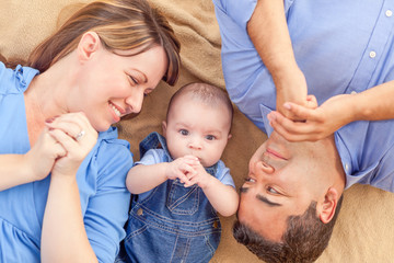 Wall Mural - Young Mixed Race Couple Laying With Their Infant On A Blanket