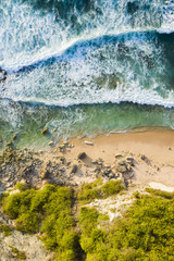 Wall Mural - View from above, stunning aerial view of a rocky shore with a beautiful beach bathed by a rough sea during sunset, Nyang Nyang Beach (Pantai Nyang Nyang), South Bali, Indonesia.