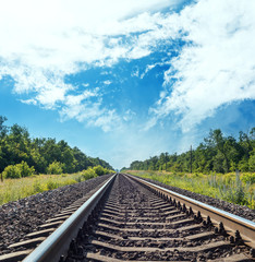 Wall Mural - one railroad to horizon in green meadow and blue sky with clouds