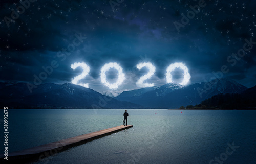 Fotomural New year background, young man standing on a jetty in a lake and looking to the