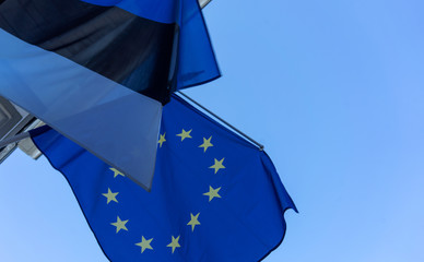 Flags of Estonia and the European Union on the building against the blue sky on a bright Sunny day