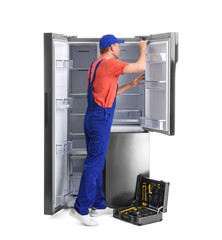 Wall Mural - Male technician repairing refrigerator on white background