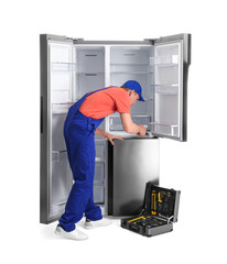 Poster - Male technician repairing refrigerator on white background