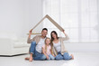 © New Africa - Happy family sitting under cardboard roof at home. Insurance concept