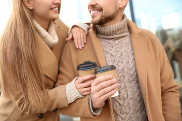 Canvas Print - Couple with cups of coffee on city street in morning, closeup