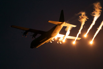 Wall Mural - Military plane firing flares during a  night flight.