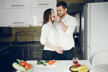 Lovely couple at home in a kithen. Woman and man prepare salad. Woman in a white shirt