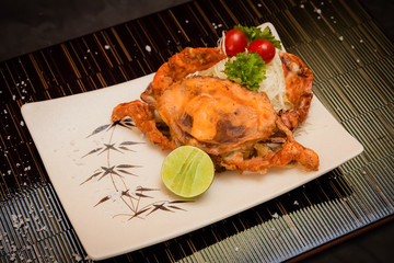 deep fried soft shell crab With salt and lime on black background.