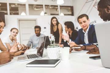 Wall Mural - A team of young office workers, businessmen with laptop working at the table, communicating together in an office. Corporate businessteam and manager in a meeting. coworking.