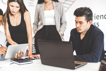 A team of young office workers, businessmen with laptop working at the table, communicating together in an office. Corporate businessteam and manager in a meeting. coworking.