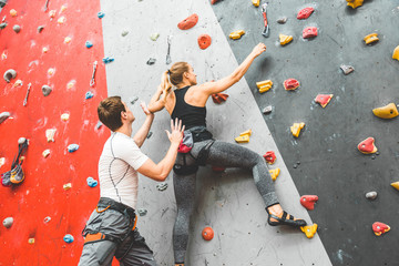 Wall Mural - couple of athletes climber moving up on steep rock, climbing on artificial wall indoors. Extreme sports and bouldering concept