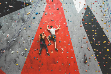 Wall Mural - couple of athletes climber moving up on steep rock, climbing on artificial wall indoors. Extreme sports and bouldering concept