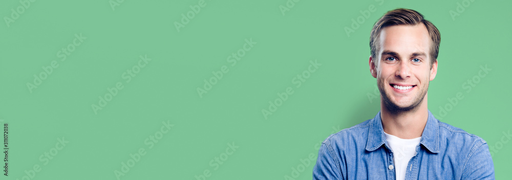 Portrait of happy man, with empty copy space area for slogan, advertising or text message, against green background. Caucasian male model in smart casual clothing, studio picture. Banner composition. - obrazy, fototapety, plakaty 