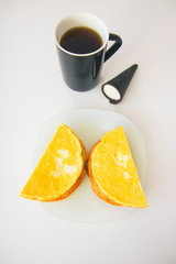 two semicircular omelettes on toasts on a white plate a black cup with coffee and a black cone with a dessert on a white background top view