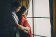 © aaalll3110 - a loving couple embraces at the window. A man and a woman look into each other's eyes. The husband hugs his pregnant wife and strokes her stomach. Valentine's day. February 14