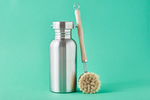 Zero Waste Concept. Eco Friendly Reusable Aluminun Bottle And Wooden Cleaning Brush On A Green Background