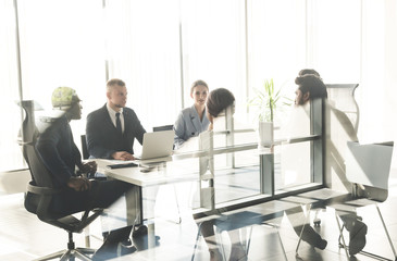 Wall Mural - Silhouettes of people sitting at the table. A team of young businessmen working and communicating together in an office. Corporate businessteam and manager in a meeting