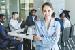 © xartproduction - Business woman stands on the background of partners. A team of young businessmen working and communicating together in an office. Corporate businessteam and manager in a meeting