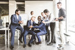 © xartproduction - A team of young businessmen working and communicating together in an office. Corporate businessteam and manager in a meeting.