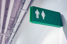 Public Toilet Sign For Restroom With Man And Woman Picture In Green Color On A White Wall Background