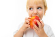 modest charming blonde child dressed in a white T-shirt eats an apple on a white background with copy space