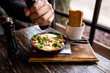 Shakshuka with eggs, tomatoes and parsley in a pan. Shakshuka is a traditional Israeli tomato stew with an egg. Fried eggs with sausages. Little frying pan with food on a wooden board. Wooden table