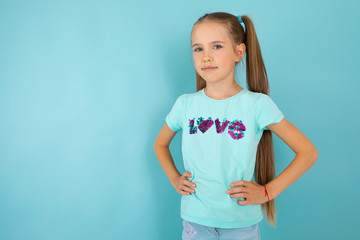 fashionable teenager girl in blue t-shirt gesticulates, portrait isolated on blue background