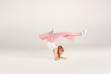 Wall Mural - Inclusive Beauty. Girl with red hair isolated on grey forearm stand legs forward concentrated