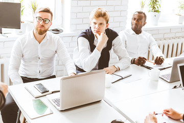 A team of young businessmen working and communicating together in an office. Corporate businessteam and manager in a meeting.