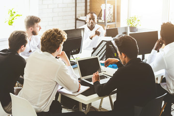 A team of young businessmen working and communicating together in an office. Corporate businessteam and manager in a meeting.