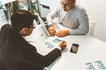 Poster - Young office worker sitting at desk, using computer. Two business man talking