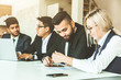 © xartproduction - A team of young businessmen working and communicating together in an office. Corporate businessteam and manager in a meeting.
