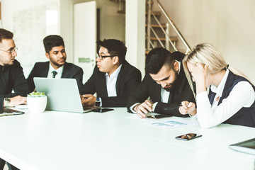 A team of young businessmen working and communicating together in an office. Corporate businessteam and manager in a meeting.